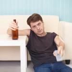 Drunk guy with bottle of beer, TV changes channels