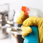 hand in protective glove holding spray. cleaning a kitchen concept