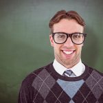 Geeky hipster smiling at camera  against green chalkboard