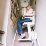 Senior woman using automatic stairlift on a staircase at her home. Medical Stairlift for disabled