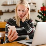 Sad woman at home using laptop computer and mobile phone