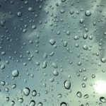 Raindrops on a window with a blue sky