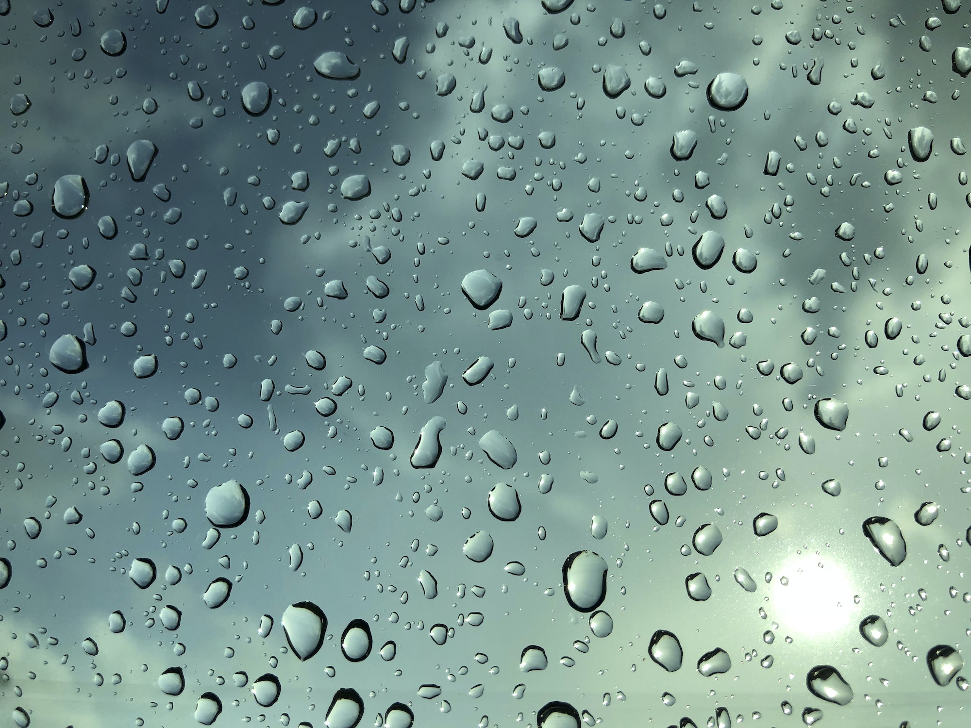 Raindrops on a window with a blue sky