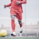 African soccer player with red outfit playing soccer.