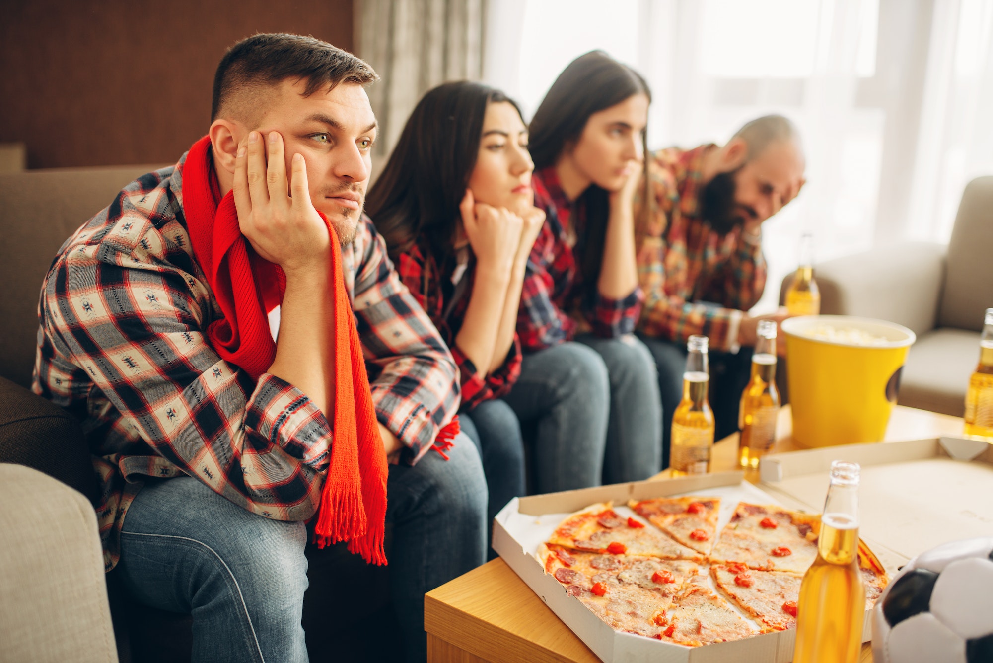 Sad friends watching TV at the boring house party