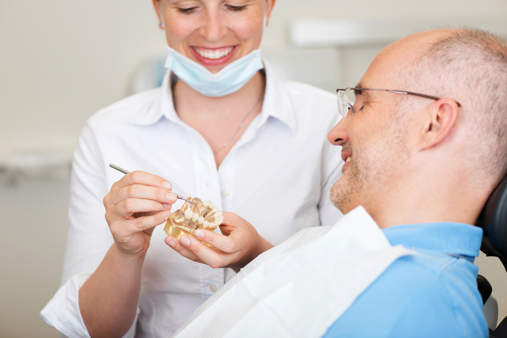 Smiling Female Dentist Explaining Artificial Teeth