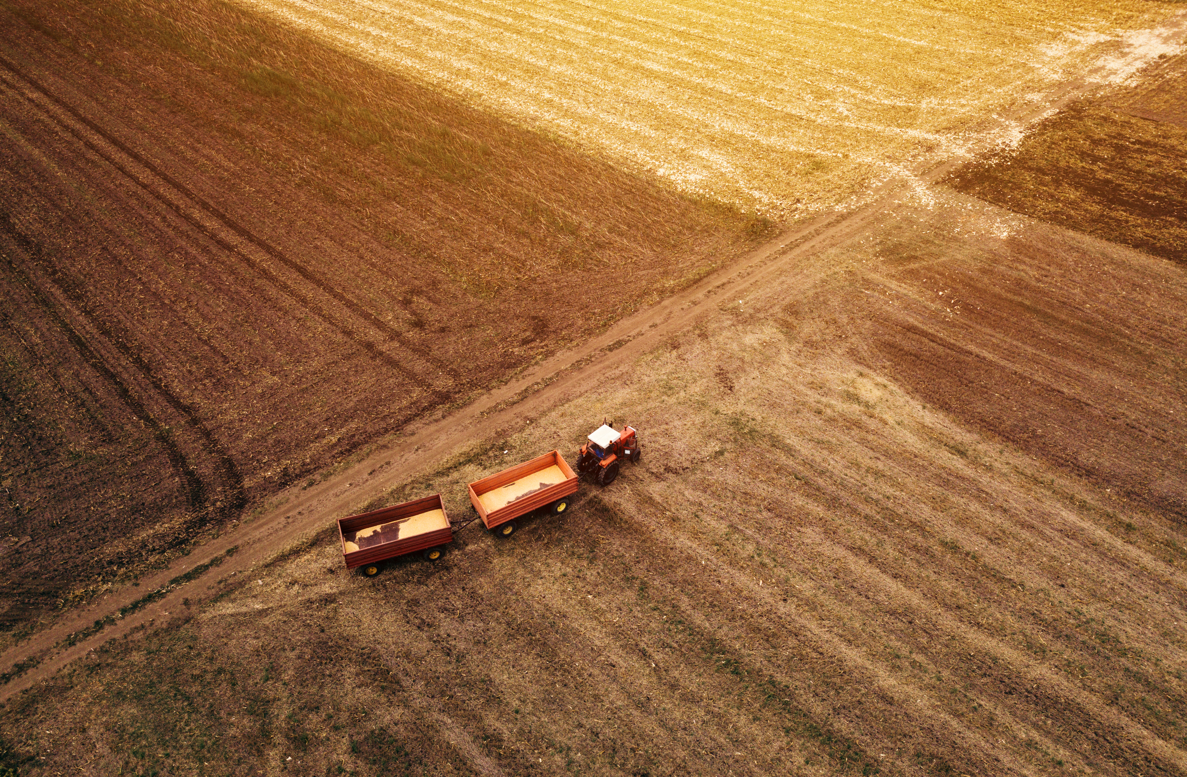 Hoe personeelstekort in de agri- en foodsector oplossen? Aerial view of agricultural tractor in the field