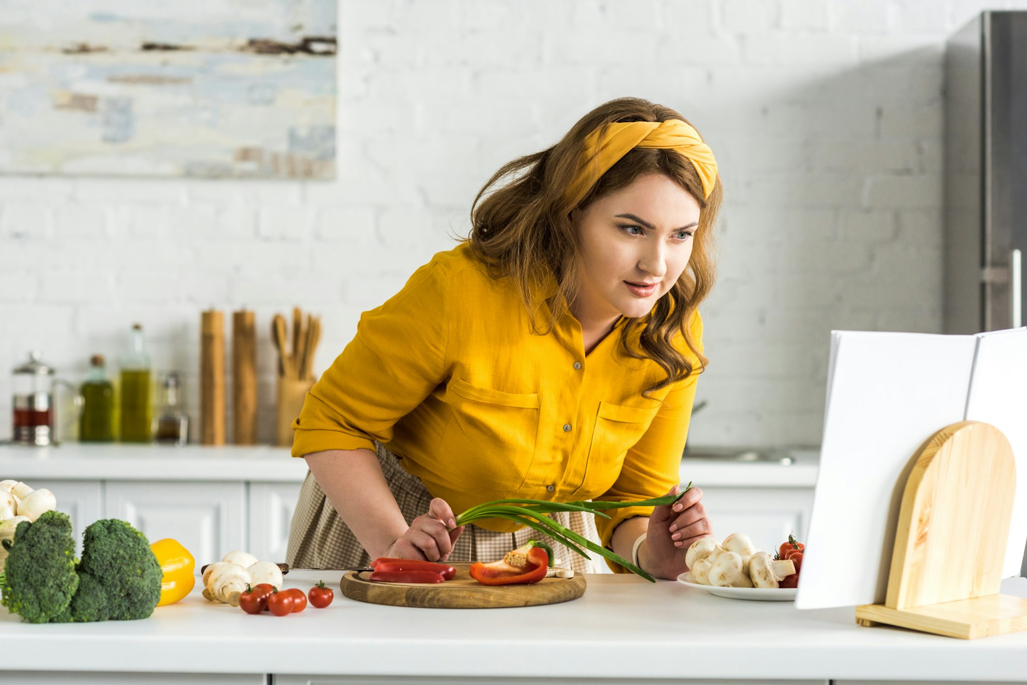 beautiful woman reading recipe in recipe book at kitchen