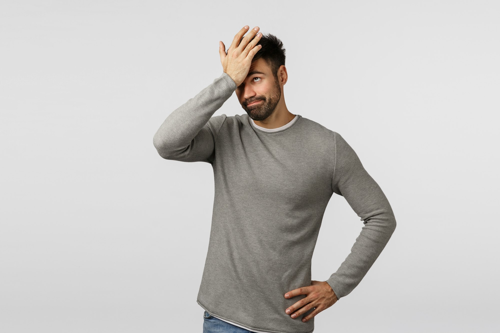 So dumb. Forgetful and displeased, tired bearded man in grey sweater, facepalm, punch forehead as