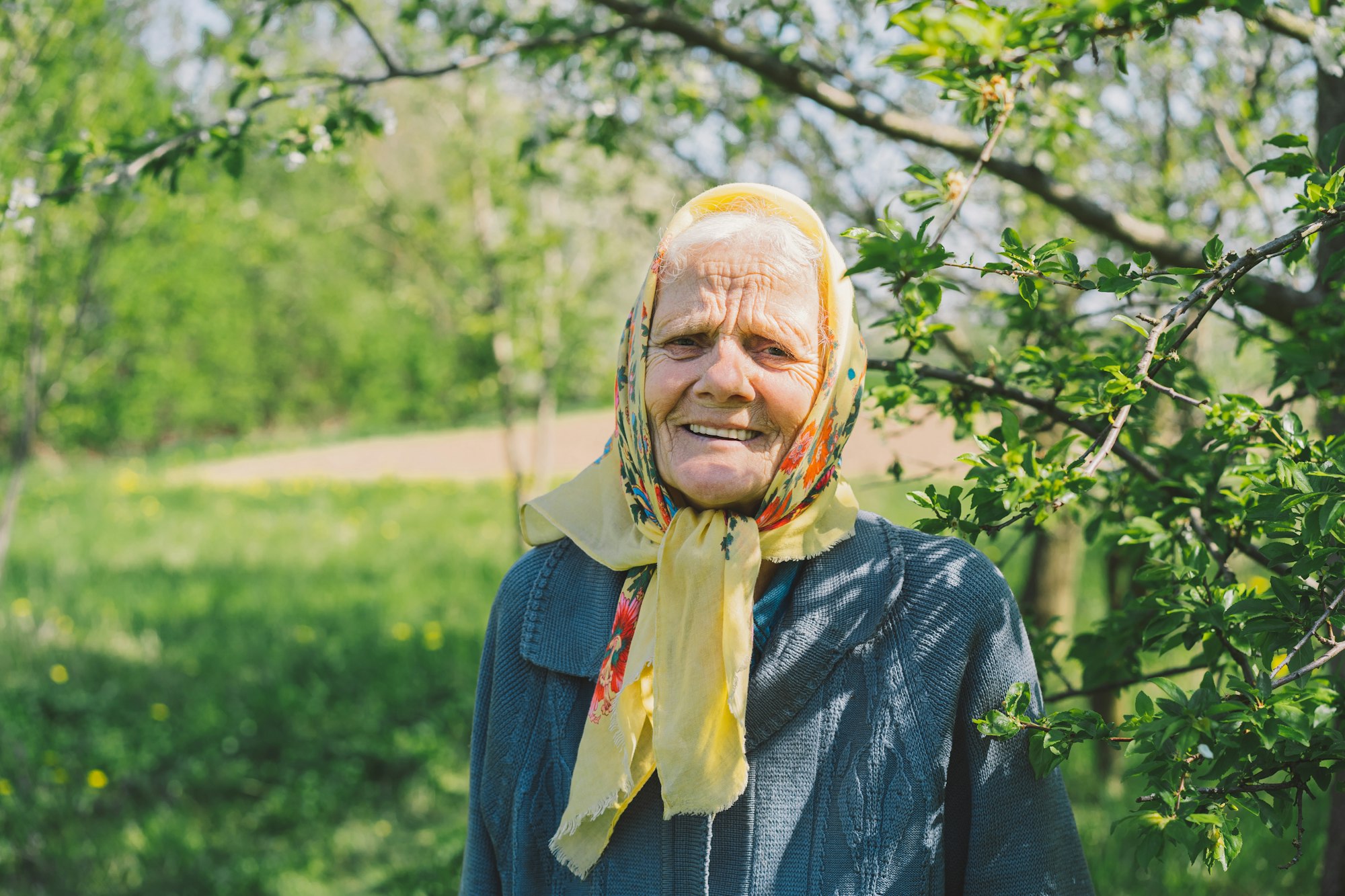 Portrait of an old happy woman in a yellow headscarf.