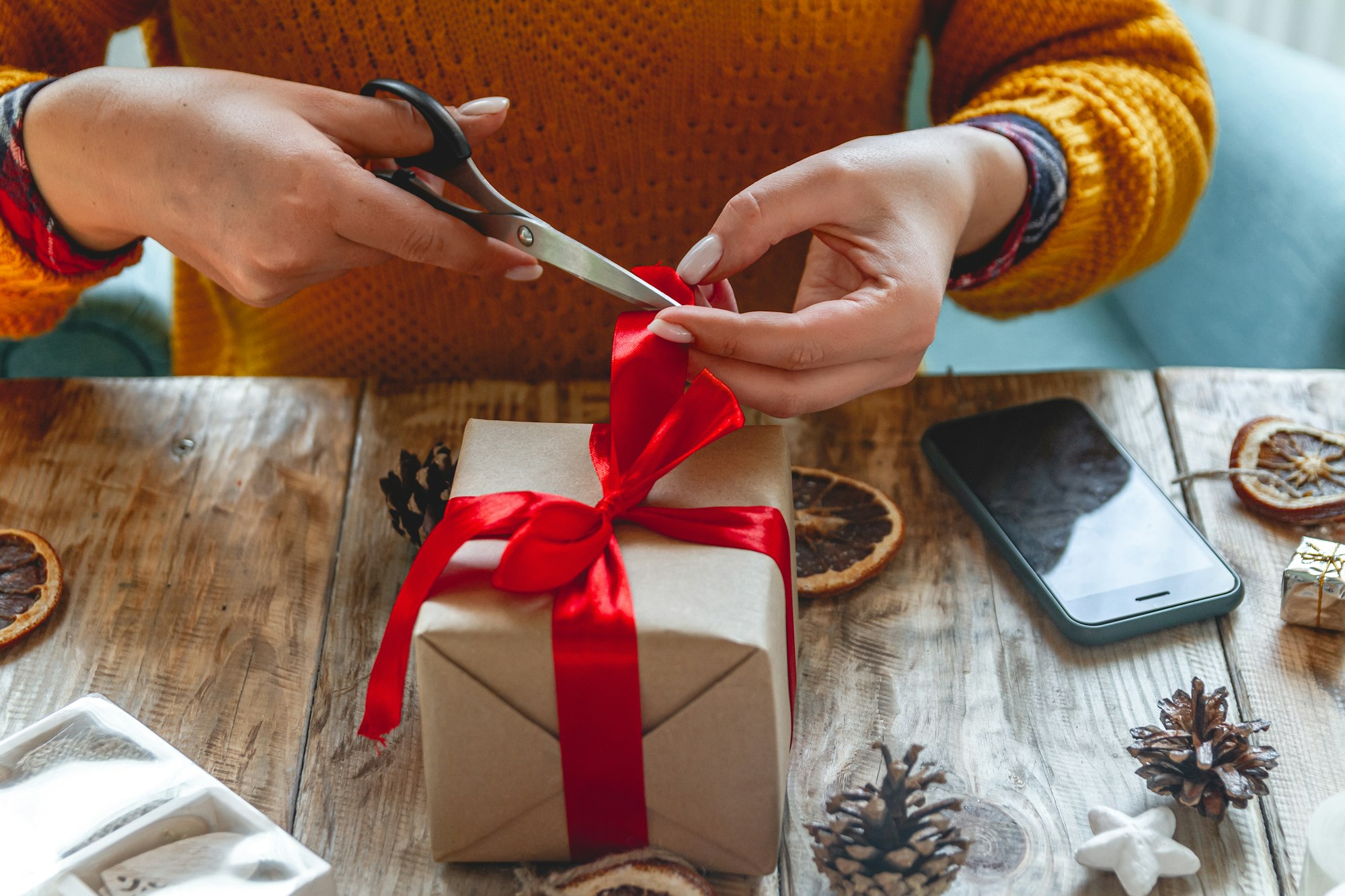 Young woman wrapping christmas present on table with new year de