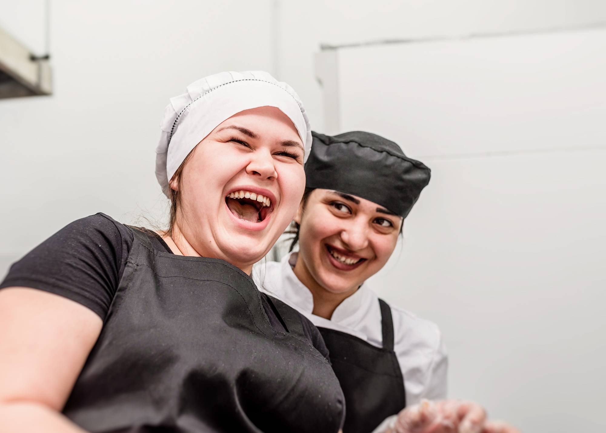 Young women cooks laughing working at the kitchen